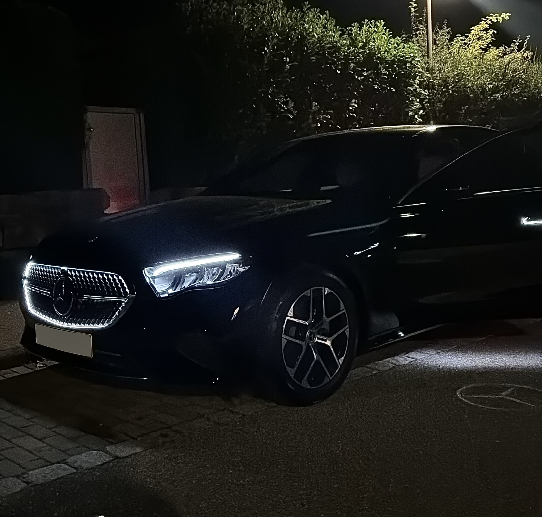 Schwarze Mercedes Limousine bei Nacht mit geöffneter Tür und auf den Boden projiziertem Stern
