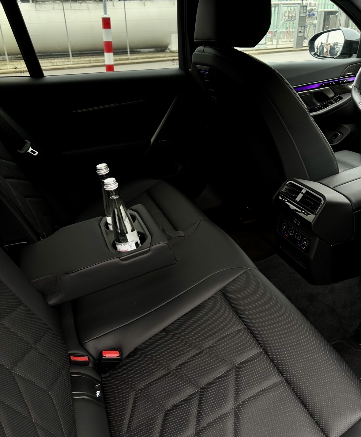 Premium-Innenraum einer Business-Class Limousine mit geschwungenen Ledersitzen, Wasserflaschen und Ambientlicht