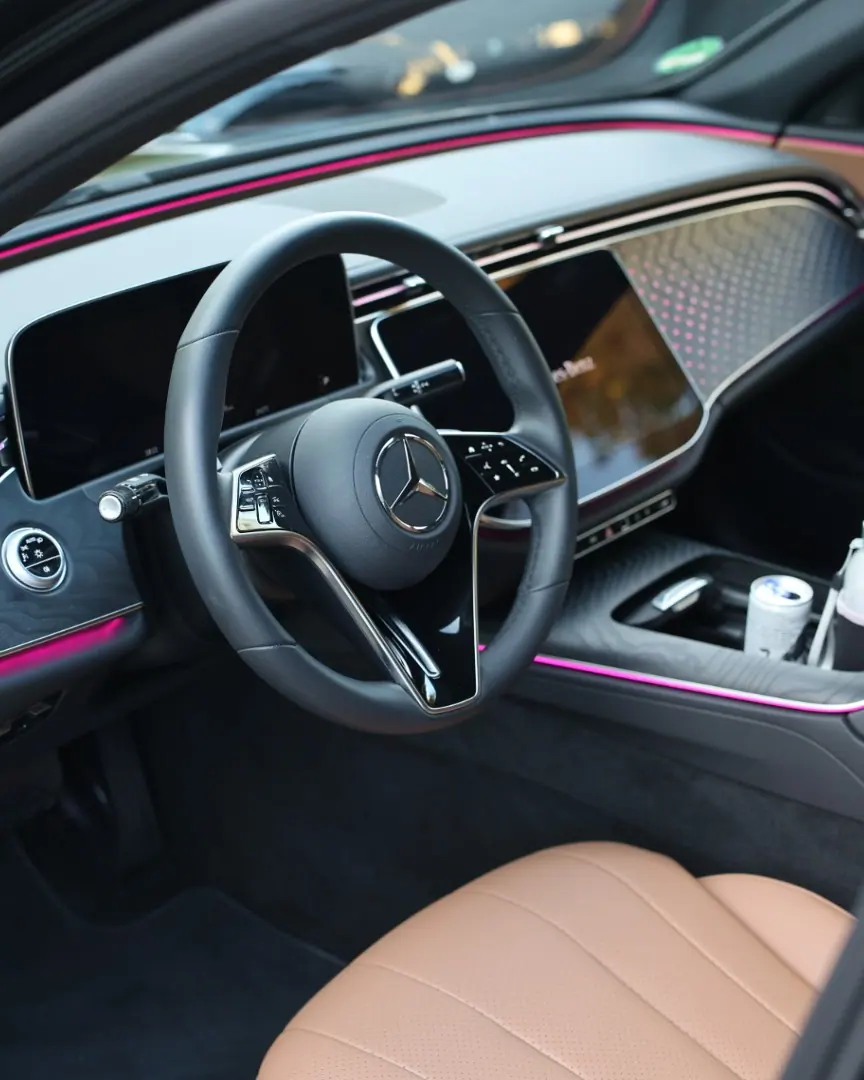 Mercedes-Fahrercockpit mit Lenkrad, digitalem Cockpit-Display und Ambientebeleuchtung — Chauffeurservice Stuttgart