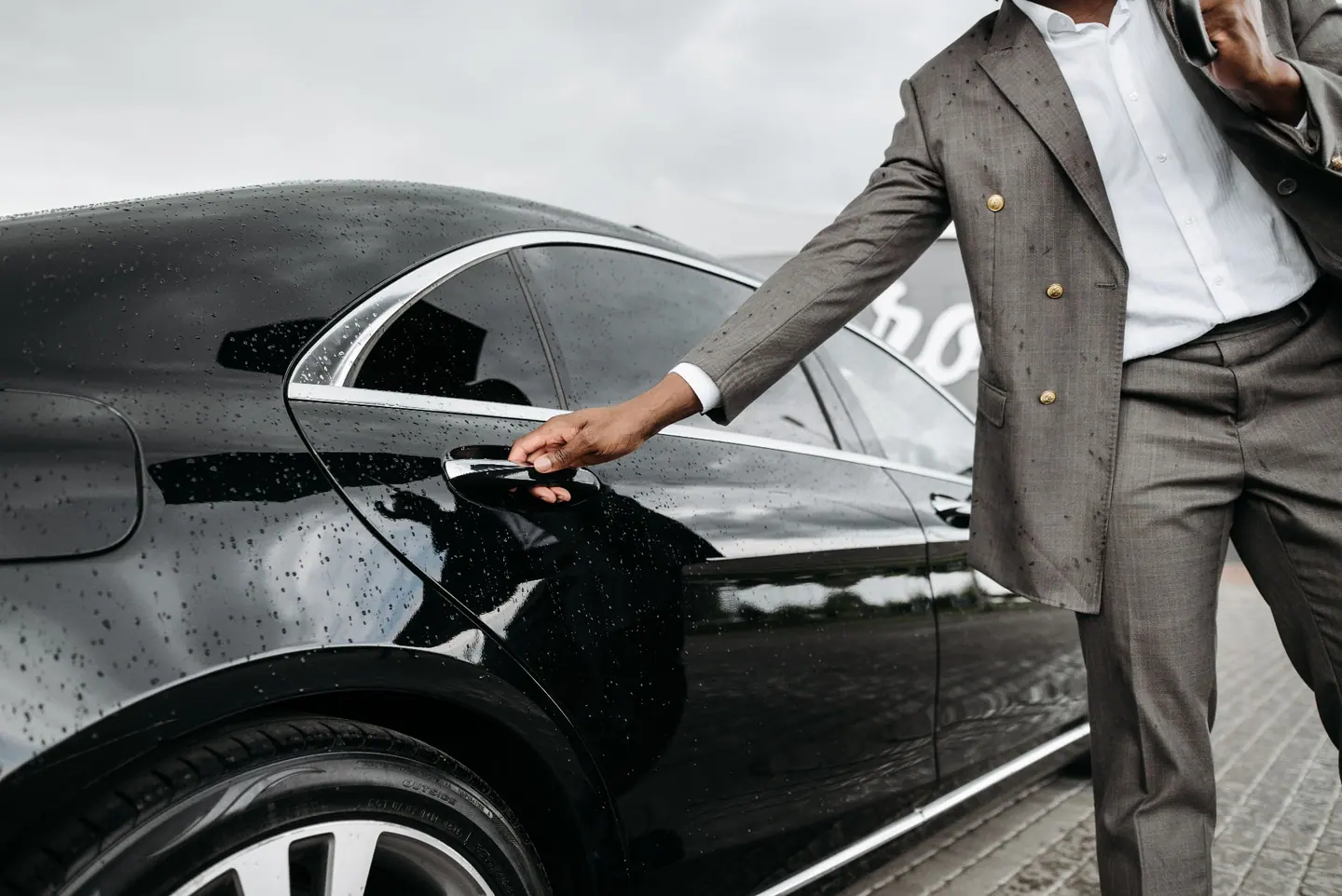 Chauffeur öffnet die Tür einer schwarzen Limousine im Regen — Firmenfahrt in der Region Stuttgart