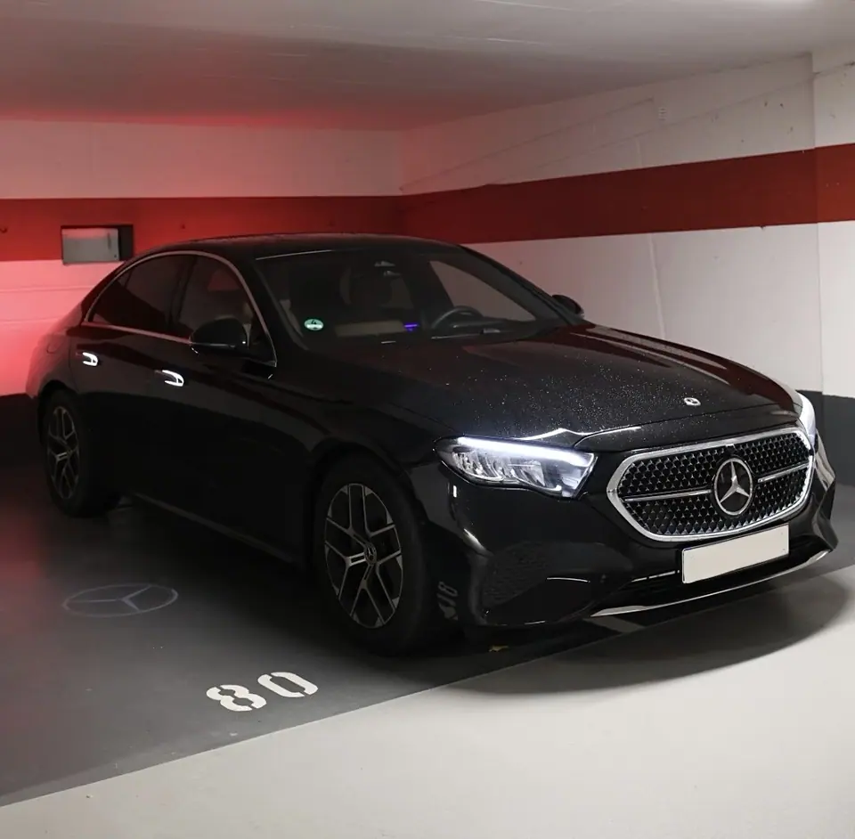 Schwarze Mercedes E-Klasse in einer Tiefgarage, Frontansicht mit auf den Boden projiziertem Stern