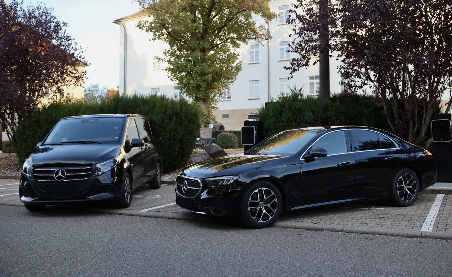 Schwarze Mercedes V-Klasse und E-Klasse nebeneinander an Ladesäulen — Chauffeurservice Stuttgart